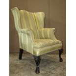 A Georgian style wing chair with swept and scrolled arms, alternating yellow striped upholstered