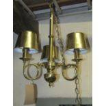 A polished brass hanging ceiling light, the simple knopped tubular stem supporting three scrolled