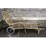 A vintage wicker portable chaise/lounger with down swept arms, wire spoke wheels and hard rubber