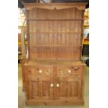 A Victorian style stripped pine kitchen dresser, the base enclosed by a pair of twin moulded