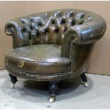 A late Victorian low green leather, upholstered tub chair with scrolled and buttoned back, raised on