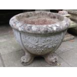 A weathered composition stone garden urn of circular waisted form with repeating grape and vine