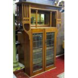 An Art Nouveau/crafts oak bookcase, enclosed by a pair of rectangular leaded light panelled doors,