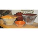 Four vintage terracotta dairy pans of varying size, one complete with cover, all with glazed