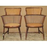 A pair of early 20th century light weight, stained beechwood stick-back elbow chairs, with cane