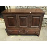 An Old English style low oak side cupboard partially enclosed by three fielded panelled doors over