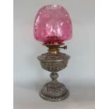 A Victorian cast spelter oil lamp with richly detailed frame work, complete with cranberry glass
