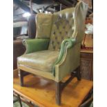 A Georgian style two tone green leather upholstered wing armchair with buttoned back, loose seat