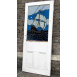 A reclaimed 1930s painted pine door, partially enclosing a coloured leaded light panel of a