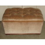 An upholstered box ottoman of rectangular form with buttoned hinged lid and stained wooden trim,