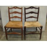 Two similar Countrymade stained beechwood rush seated dining chairs with shaped ladder-backs