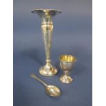A collection of silver comprising a silver eggcup and spoon, flared vase and small thimble (4)
