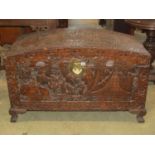 An Eastern camphor wood domed top chest with profusely carved detail, brass lock plate and lasp