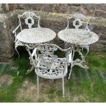 A pair of weathered cream painted cast aluminium garden terrace tables of circular form with