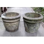 A pair of weathered cast composition stone garden planters of circular tapered form with raised