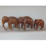Tribal Interest - Two carved hardwood elephants, together with a further smaller example, the
