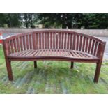 A stained and weathered teak banana shaped garden bench with slatted seat and back (AF), 150 cm long