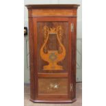An interesting Edwardian mahogany hanging corner cupboard, the panelled door with musical panoramas,