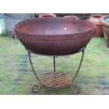 A weathered Kadai iron work fire bowl with riveted seams, ring handles and stand with simple