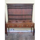 A Georgian oak Welsh dresser and plate rack, the base enclosed by three frieze drawers,