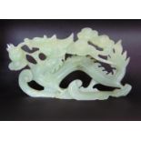 A carved green stone group of a dragon chasing a pearl through clouds, 30cm long approx