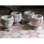 A set of four cylindrical garden urns with Greek key borders and fruiting vine detail, 24cm high