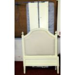 A single bedstead with moulded and painted framework and upholstered padded headboard raised on