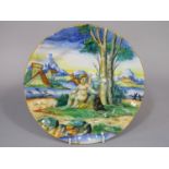 A continental tin glazed earthenware plate with polychrome painted decoration of a cupid in a