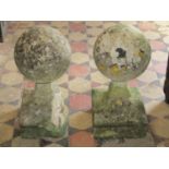 A pair of antique weathered limestone capitals in the form of balls on waisted square cut