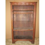 A small oak freestanding open bookcase, with two adjustable shelves and carved foliate detail,