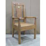 An oak open armchair with chamfered frame, solid seat, through jointed arms and broad splat, with