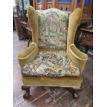 A 19th century upholstered wing chair raised on claw and ball feet with hand worked tapestry seat