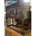 An old English style oak side cupboard with rising lid over a carved panelled front, partially