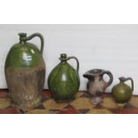 An old stoneware flagon with partial green glazed loop handle and neck, two further smaller examples