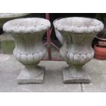 A pair of composition stone campana shaped garden urns with flared rims, lobed bodies and square cut