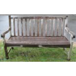 A weathered teak garden bench with slatted seat, back and scrolled arms, 5ft long