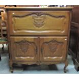 A medium to light oak side cupboard, freestanding and enclosed by three moulded and fielded panelled