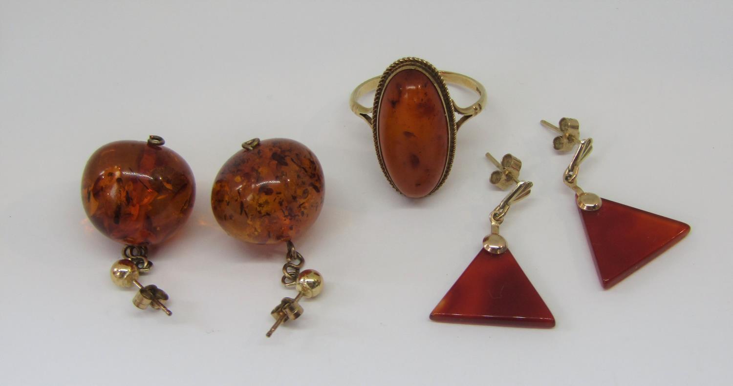 Group of 9ct amber jewellery comprising an oval ring, size Q/R and two pairs of drop earrings (5)