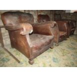 A pair of tan leather upholstered easy chairs with swept and rolled arms, studded detail and