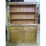 A stripped pine farmhouse kitchen dresser, the base enclosed by a pair of panelled doors beneath two