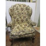A good quality Georgian style wing chair with scrolled arms, raised on cabriole forelegs, united