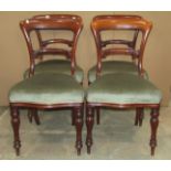 A set of four Victorian mahogany balloon-back dining chairs with scrolled splats, upholstered