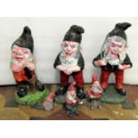 Three small cast composition stone garden gnomes in varying poses with brightly painted weathered