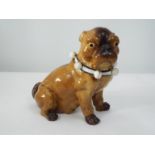 A 19th century porcelain figure of a seated Pug, the collar supporting bells with painted finish,