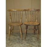 A harlequin set of four stripped elm and beechwood Swedish stick back kitchen chairs with circular