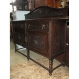 A carved oak sideboard with lions mask and scrolling foliate detail and shallow raised arch back