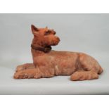 A Victorian terracotta figure of a recumbent terrier with later leather collar, 36 cm in length