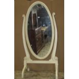 A cheval mirror/glass of oval form with moulded frame, scrolled supports, and all over painted and