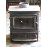A cast iron stove enclosed by a rectangular and slightly arched glazed panelled door over a