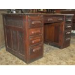 An early 20th century oak kneehole twin pedestal desk with panelled frame and fitted with an
